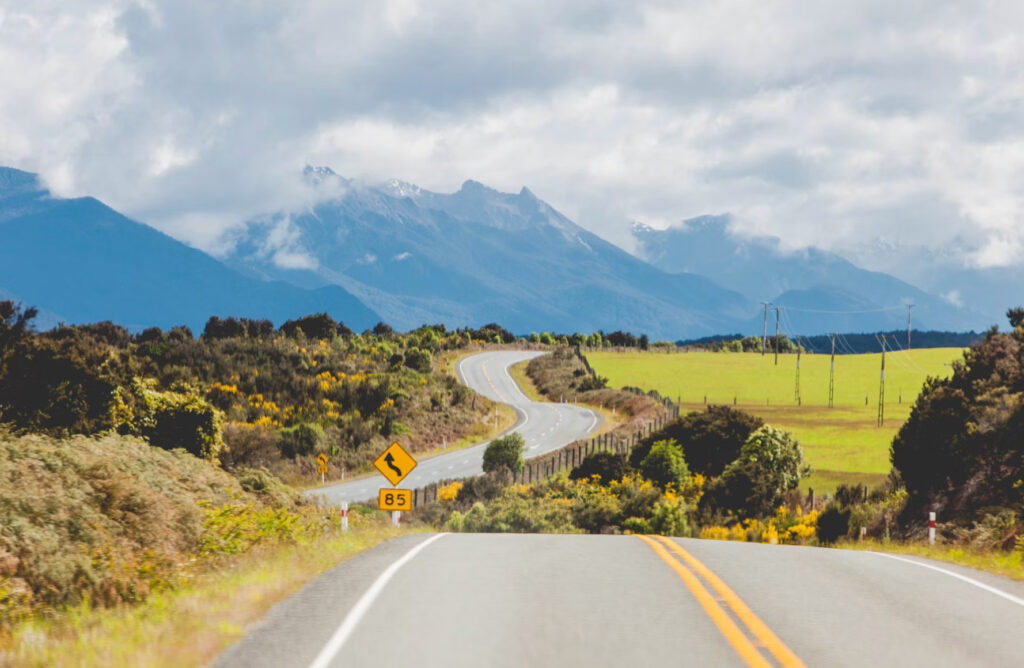 Winding rural road leading towards mountains.