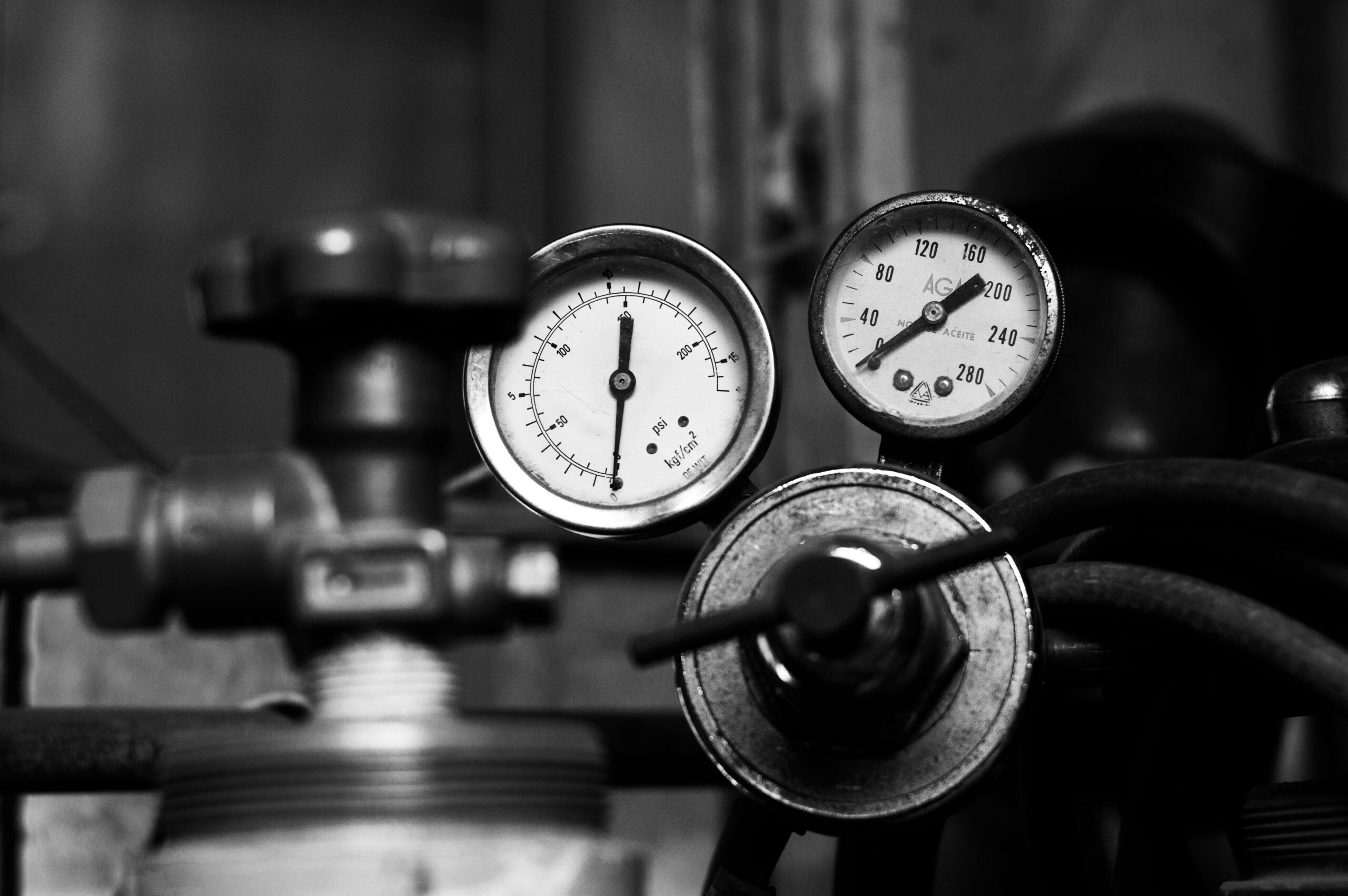 Industrial pressure gauges connected to pipes and mechanical equipment in a manufacturing environment.