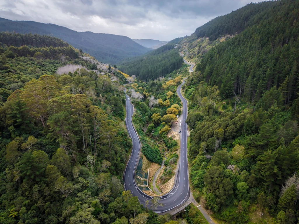 A mountainous, tree-filled landscape with a sharply curved road.