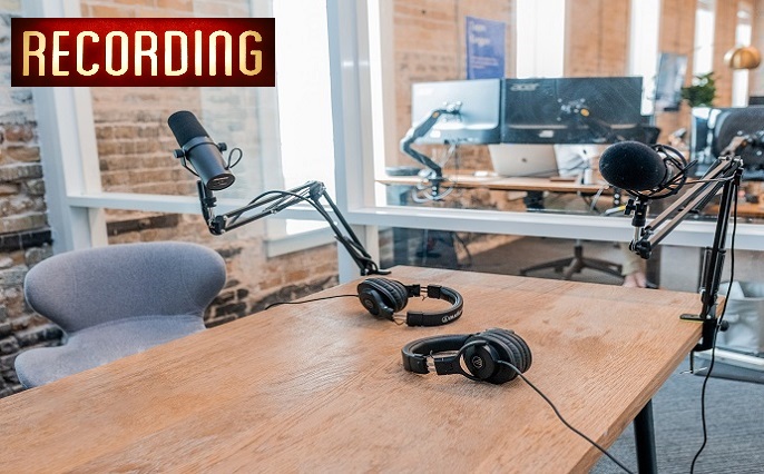 Two microphones and headphones arranged on a table in a podcast recording studio.
